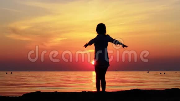 一个穿着短裙子的美丽女人的剪影在大海和日落的背景下的海边年轻女子视频的预览图
