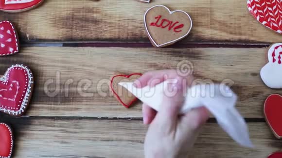 心形饼干装饰工艺与粉红色奶油特写女性手握一管粉红色奶油视频的预览图