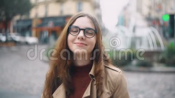 年轻微笑的学生戴着眼镜看着相机喝着茶的肖像在法国巴黎散步的快乐女人视频的预览图