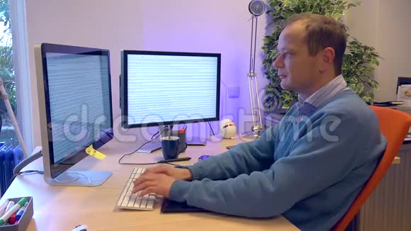 一个男人用两个屏幕在电脑后面打字视频的预览图
