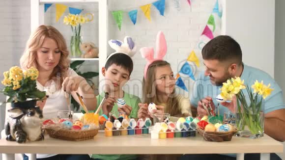 快乐的母亲父亲和孩子们在节日绘画和装饰鸡蛋时玩得开心视频的预览图