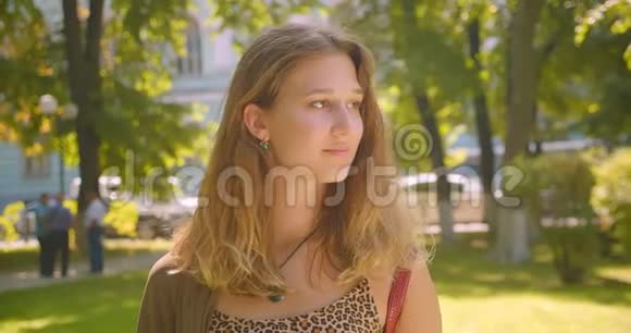 年轻漂亮的白种人女性幸福地站在公园里的特写镜头视频的预览图