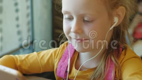 学龄前女孩在室内使用耳机电脑视频的预览图