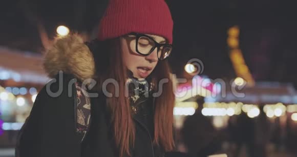 年轻美丽的白种人妇女使用智能手机在城市夜晚手持户外的肖像视频的预览图