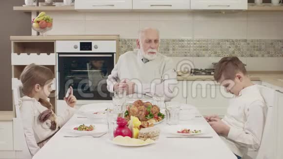 在一家人吃饭前爷爷和孙子们在餐桌上交流视频的预览图