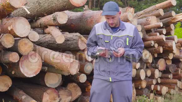 快乐的工人伐木工或木匠有一大笔钱靠近一堆原木锯木成功商业概念视频的预览图