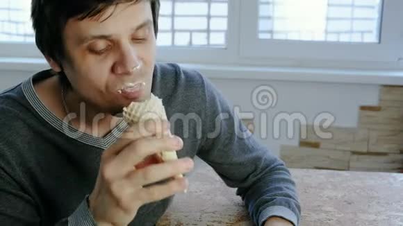 年轻的坏蛋坐在窗边在家吃冰淇淋视频的预览图