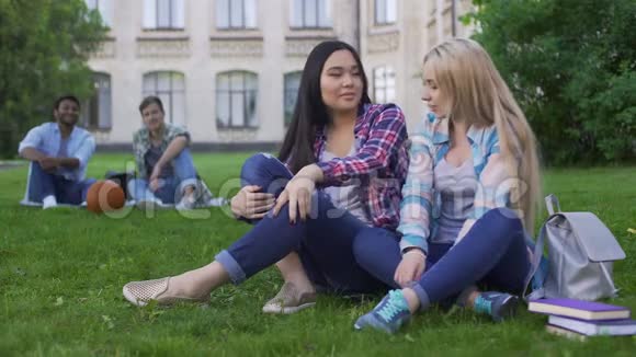 学生们坐在草坪上讨论新衣服的混血朋友视频的预览图