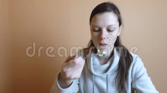 穿灰色夹克的疲惫的女人布鲁内特下班后吃蔬菜沙拉视频的预览图