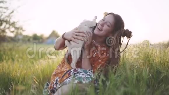 美丽的嬉皮士女人带着可怕的鸟在绿草中带着她的小狗狗在日落时在户外玩得很开心视频的预览图