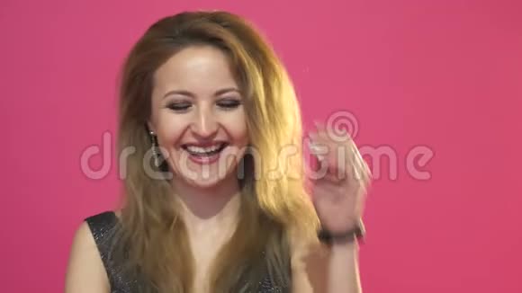 站在粉红色背景上的一个笑女人的肖像视频的预览图