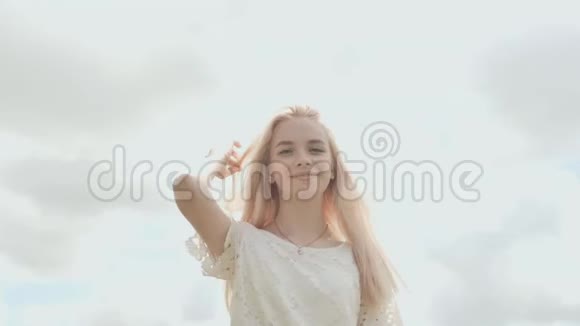 一个夏天年轻的俄罗斯女孩金发碧眼在白色的天空上摆姿势视频的预览图