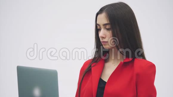 年轻商务小姐的形象孤立在灰色背景上值得用灰色笔记本电脑穿着红色衣服视频的预览图