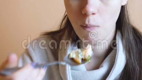 一个穿灰色夹克的女人吃蔬菜沙拉手和嘴都贴了上去视频的预览图