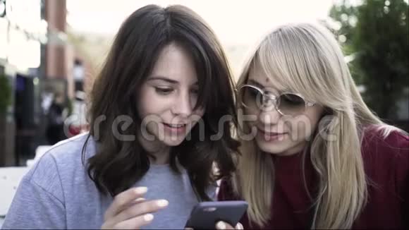 两个女朋友在户外咖啡馆用智能手机上网视频的预览图