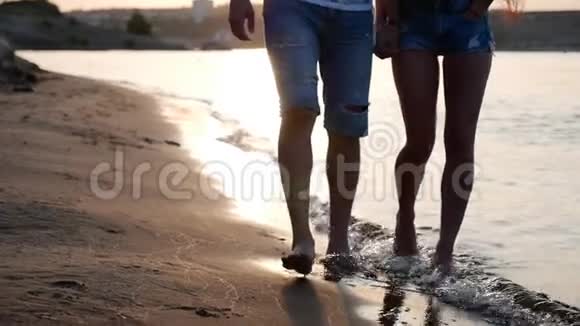 幸福夫妇牵着手漫步在岸边赤脚在沙滩上踏着海浪拥抱着视频的预览图