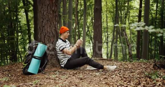 在森林中使用智能手机放松男性游客视频的预览图