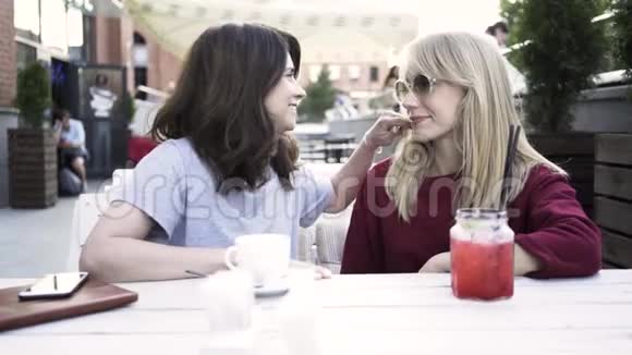 两个女朋友在户外咖啡馆分享秘密视频的预览图