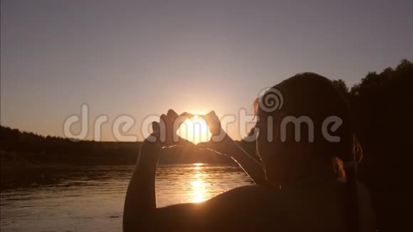 夕阳西下河里美丽的姑娘在水的映衬下双手呈心形视频的预览图