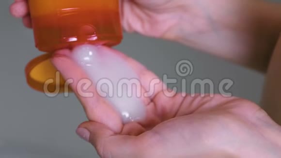 女人把洗发水从橙色的瓶子到手洗头双手特写视频的预览图