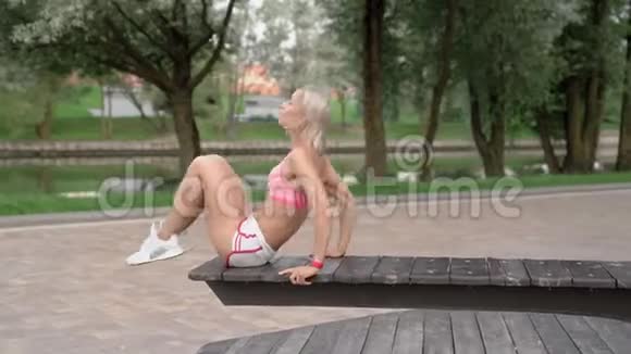 年轻女子在公园的长椅上做腹肌练习视频的预览图