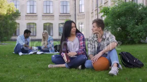 学生夫妇坐在大学附近的草地上谈笑风生初恋视频的预览图