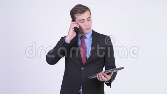 年轻快乐的英俊商人用手机和数码平板电脑视频的预览图