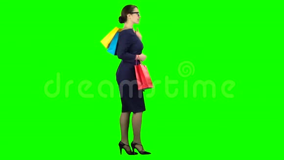 手里拿着包裹购物的女孩正沿着街走绿色屏幕侧视图视频的预览图