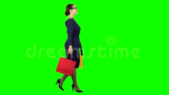 手里拿着购物包的女人正沿着街走绿色屏幕侧视图视频的预览图