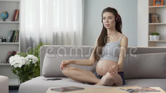 坐在耳机里锻炼的孕妇怀孕瑜伽音频指南视频的预览图