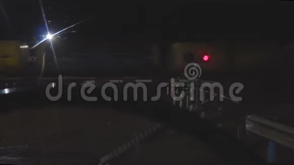 在一列过往列车的背景下夜间在一个铁路十字路口闪烁红色交通灯视频的预览图