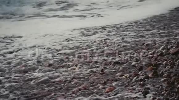 慢镜头拍摄泡沫的海浪覆盖卵石海滩视频的预览图