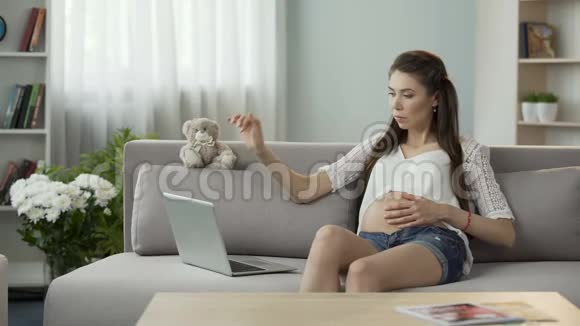 准妈妈坐在沙发上用手提电脑了解怀孕情况视频的预览图