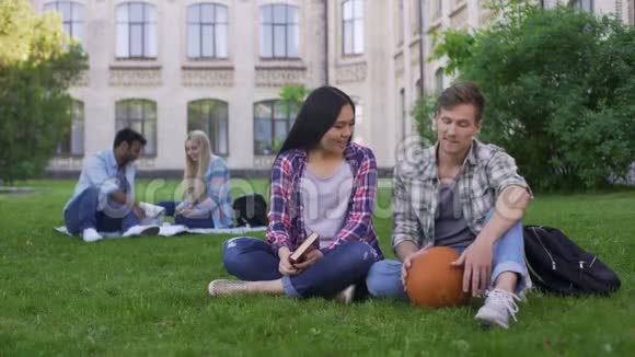 学生坐在校园草坪上调情男生试图打动女生视频的预览图
