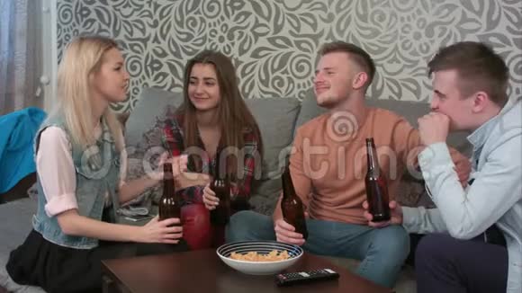一群微笑的朋友坐在沙发上品尝一瓶啤酒视频的预览图