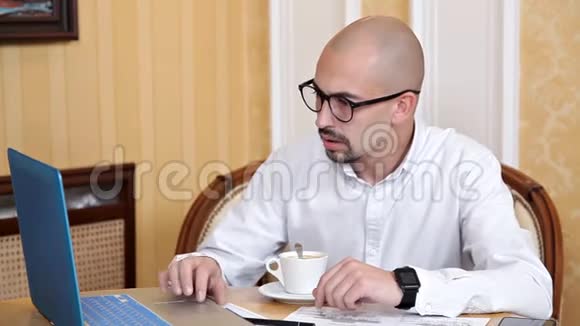 商务人员和技术概念戴眼镜的商人手提电脑喝咖啡或茶视频的预览图