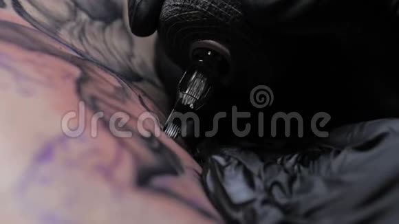 近距离纹身艺术家展示了一个客户背上有油漆的黑色纹身的过程视频的预览图