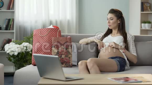 孕妇坐在沙发上拿着购物袋购物视频的预览图