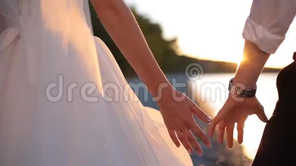在日落的婚礼日一对浪漫的新娘和一对新郎牵手视频的预览图
