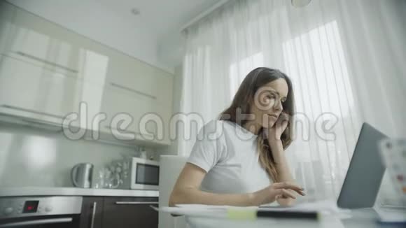 快乐的女人在厨房用笔记本电脑工作使用笔记本的女性视频的预览图