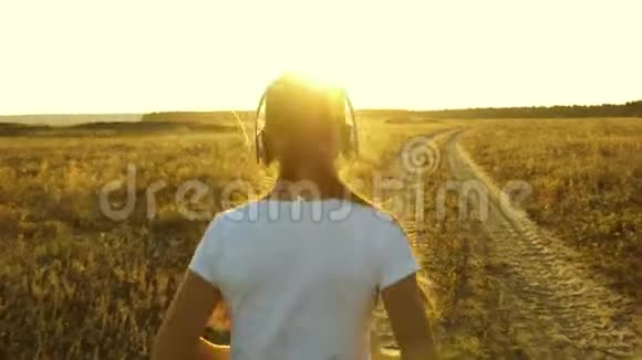 戴着耳机的运动女孩正在慢跑一个年轻女孩正在日落时训练听音乐视频的预览图