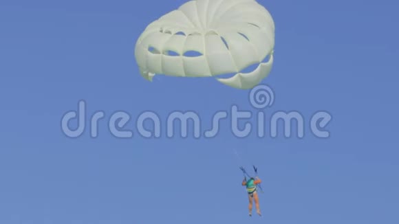 无法辨认的人在晴朗的阳光下驾驶白色降落伞视频的预览图