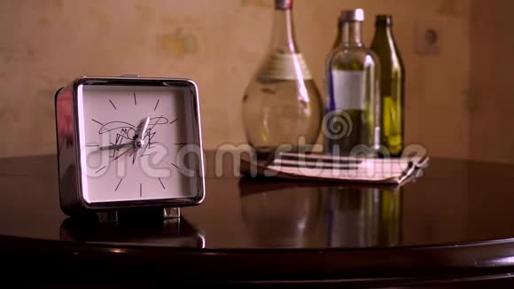 在一张光滑的棕色木桌上有一个反光有一个白色表盘一个钟和一本便签簿的方形银视频的预览图
