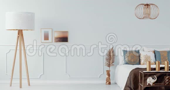 在明亮的卧室内部的一张床上方有一盏金色的台灯里面有一把金色的扶手椅视频视频的预览图
