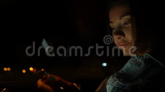 晚上坐在车里用手机的年轻女子视频的预览图
