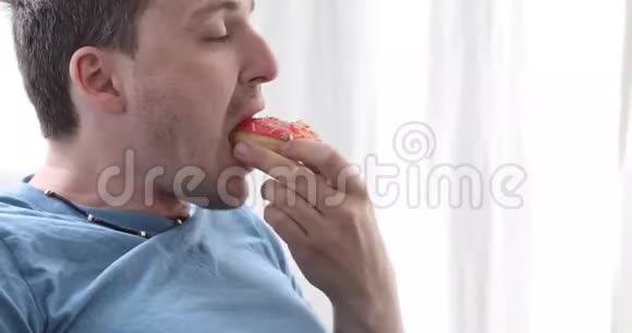 男人正在吃一个粉红色的甜甜圈特写视频的预览图