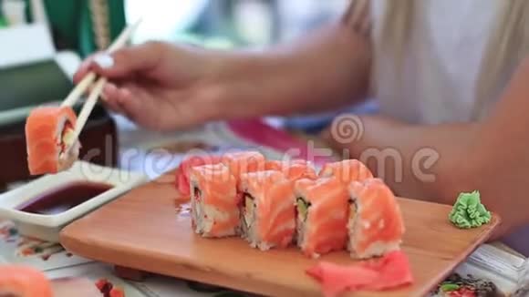 女性手拿筷子的特写镜头扣篮时髦地将寿司做成酱油视频的预览图