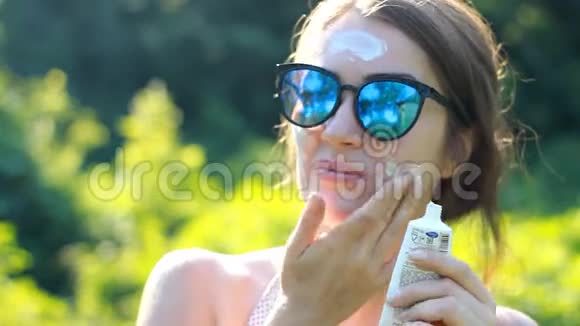 一位年轻的女士正在从阳光下涂上防晒霜视频的预览图