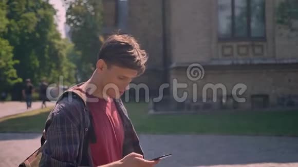 年轻的帅哥在夏天的白天走在街上敲着智能手机交流理念视频的预览图