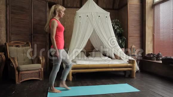 年长的女人早上在卧室练习瑜伽视频的预览图